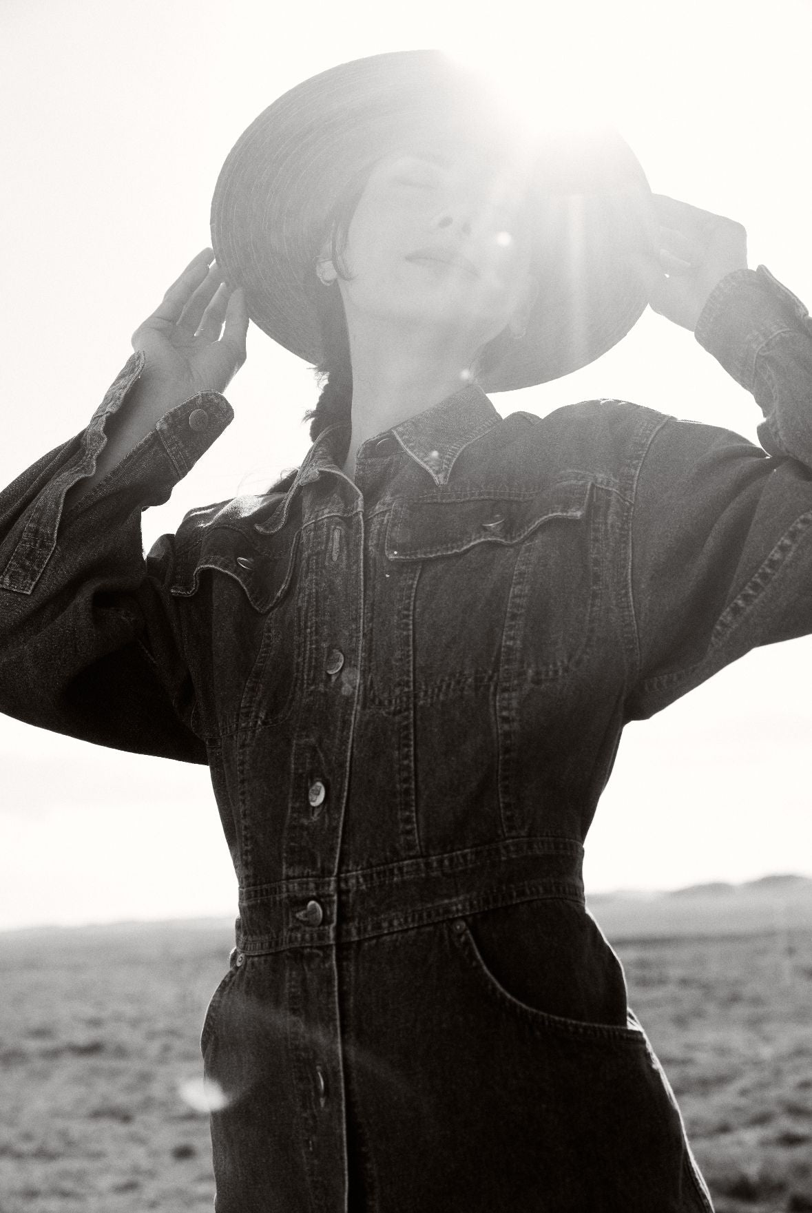 Une femme portant une combinaison en jean et un chapeau de paille dans le désert.
