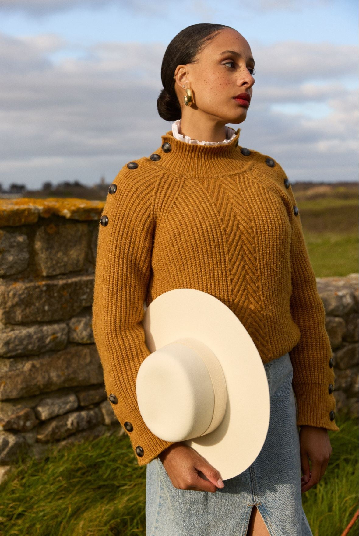 Femme portant un chandail jaune et un chapeau blanc.