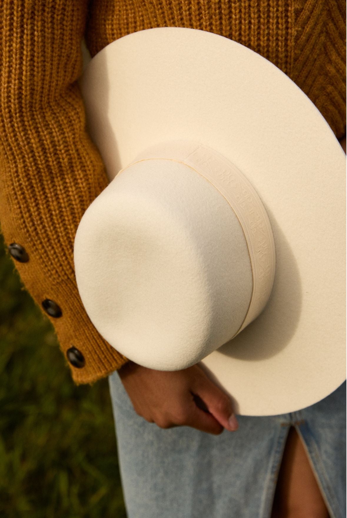 Femme portant un chandail jaune et un chapeau blanc en feutre de laine fabriqué en france 