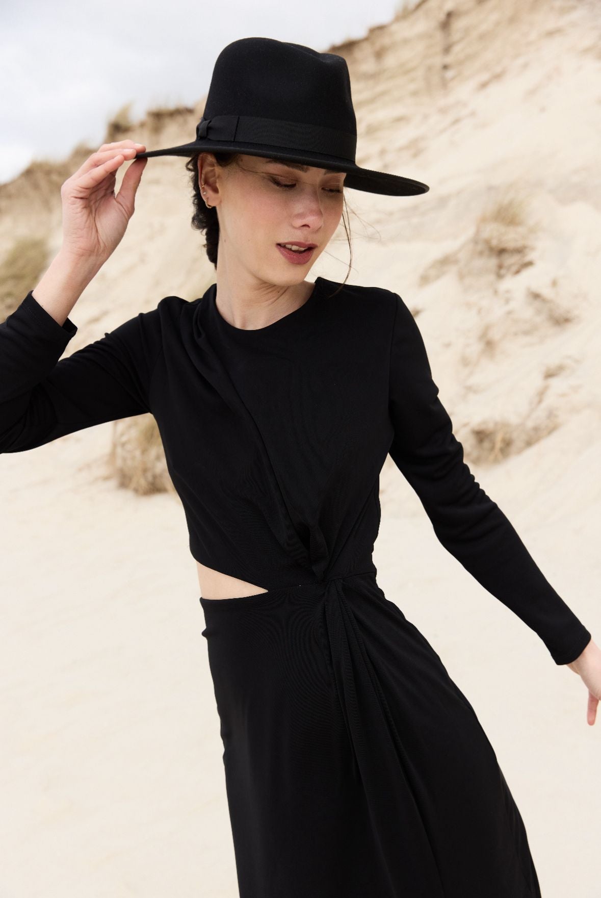 femme en robe noire et chapeau noir sur la plage