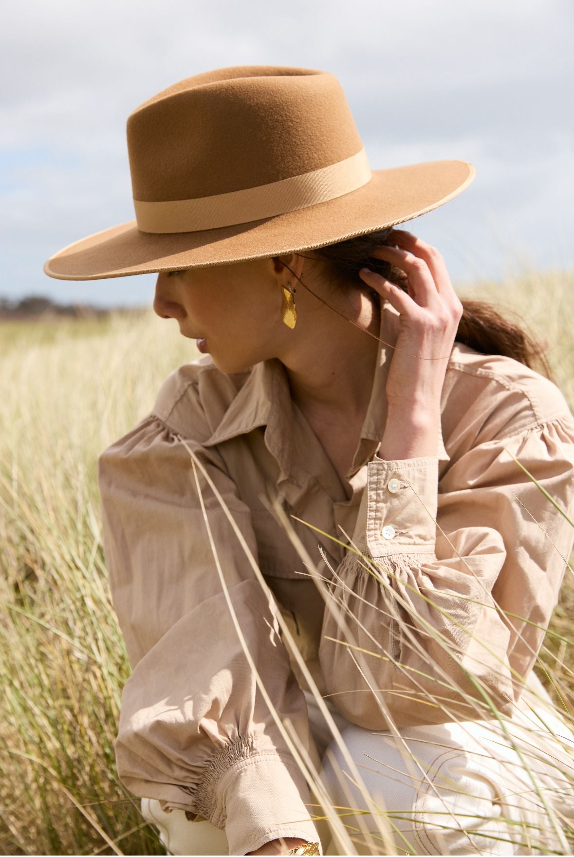 femme avec un chapeau en feutre de laine fabriqué en france  assise dans de hautes herbes