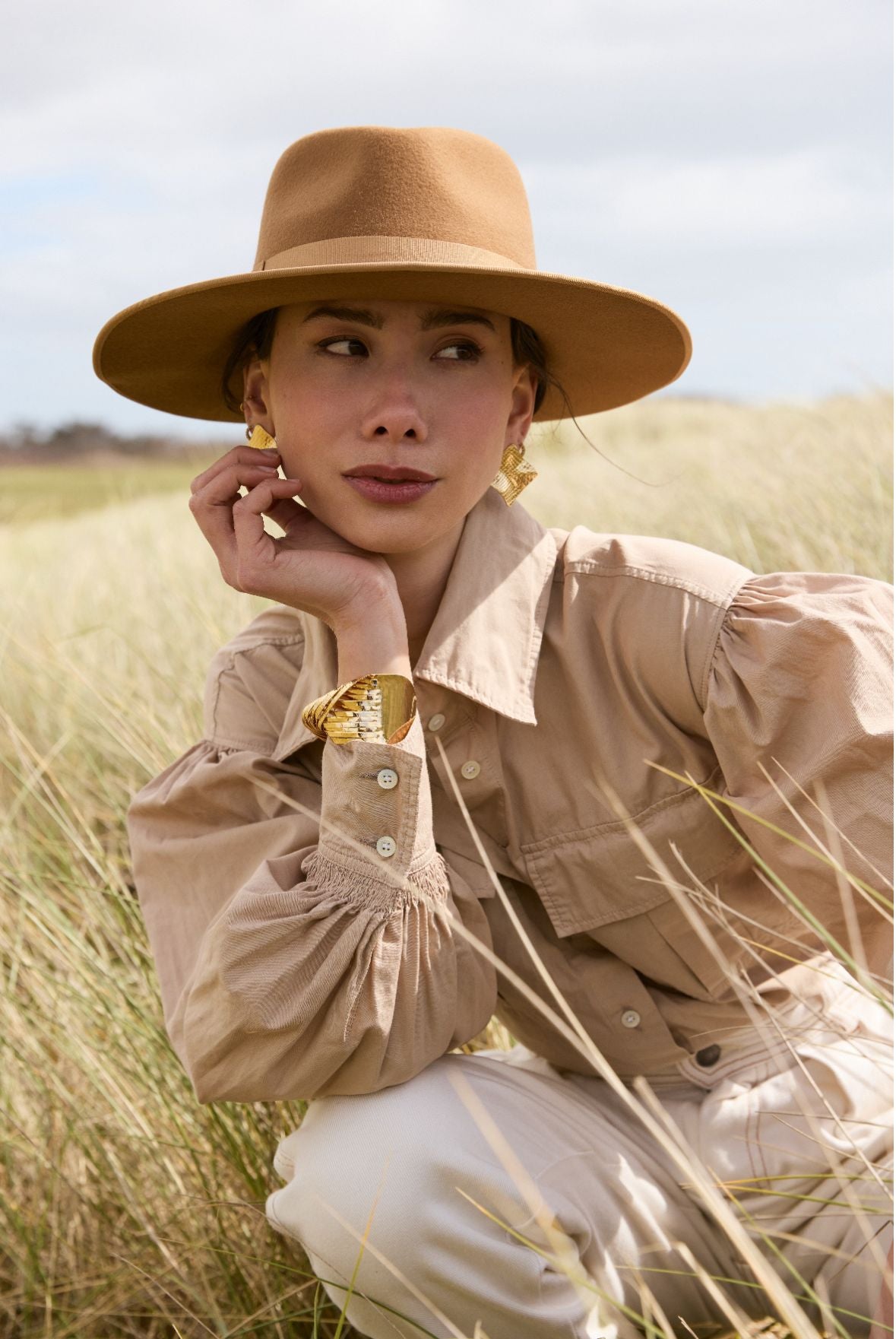 femme avec un chapeau en feutre de laine fabriqué en france  assise dans de hautes herbes